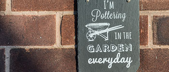 I'm pottering in the garden everyday slate garden sign hanging against a brick wall space maximise