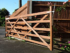 An openes field gate on a driveway painted brown