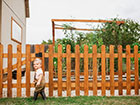 A todler walking alongside a Picket palisade fence